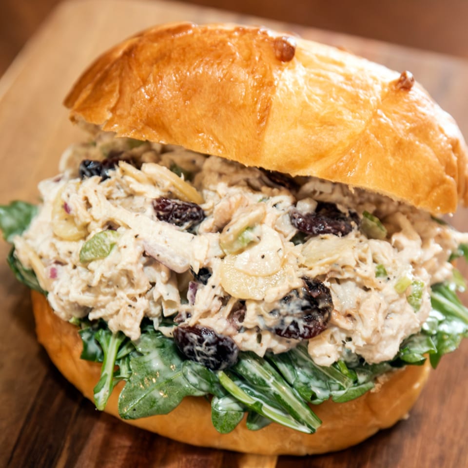 Brownsville Deli's chicken salad sandwich with arugula, raisins, and almonds on a brioche bun.
