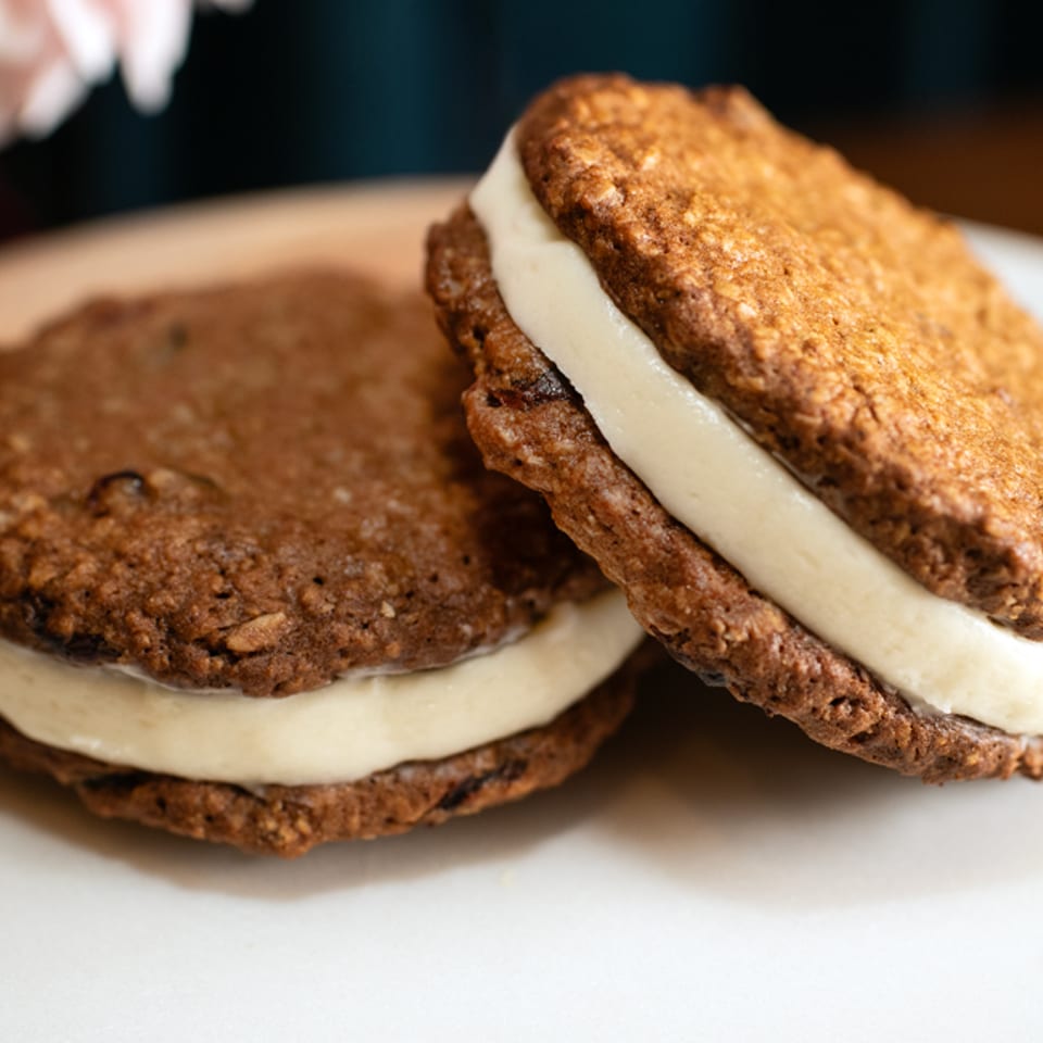 Two oatmeal cream pies with white filling on a white plate at Brownsville Deli.