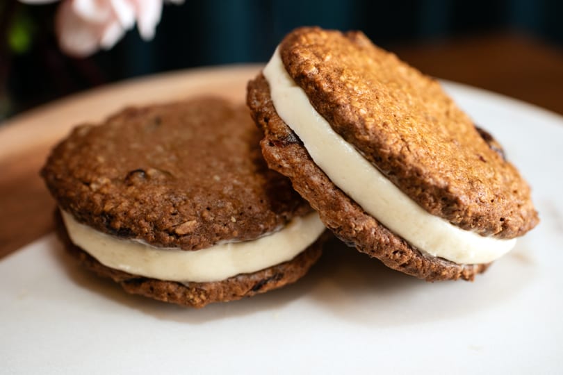 Two oatmeal cream pies with white filling on a white plate at Brownsville Deli.