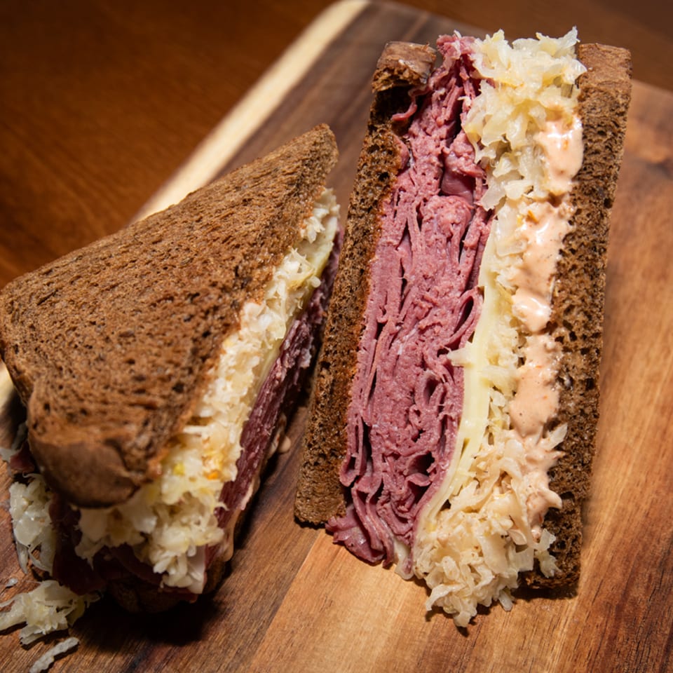 Brownsville Deli's Reuben sandwich, cut in half, with pastrami, sauerkraut, and Russian dressing on rye.
