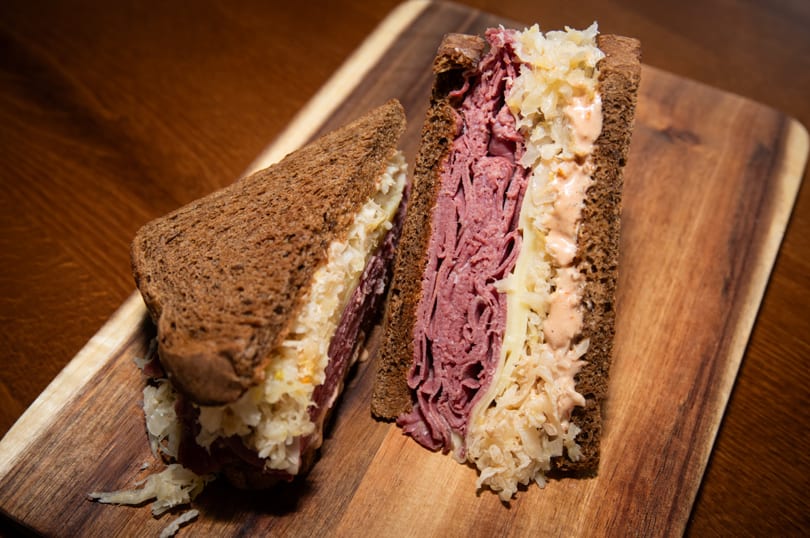 Brownsville Deli's Reuben sandwich, cut in half, with pastrami, sauerkraut, and Russian dressing on rye.